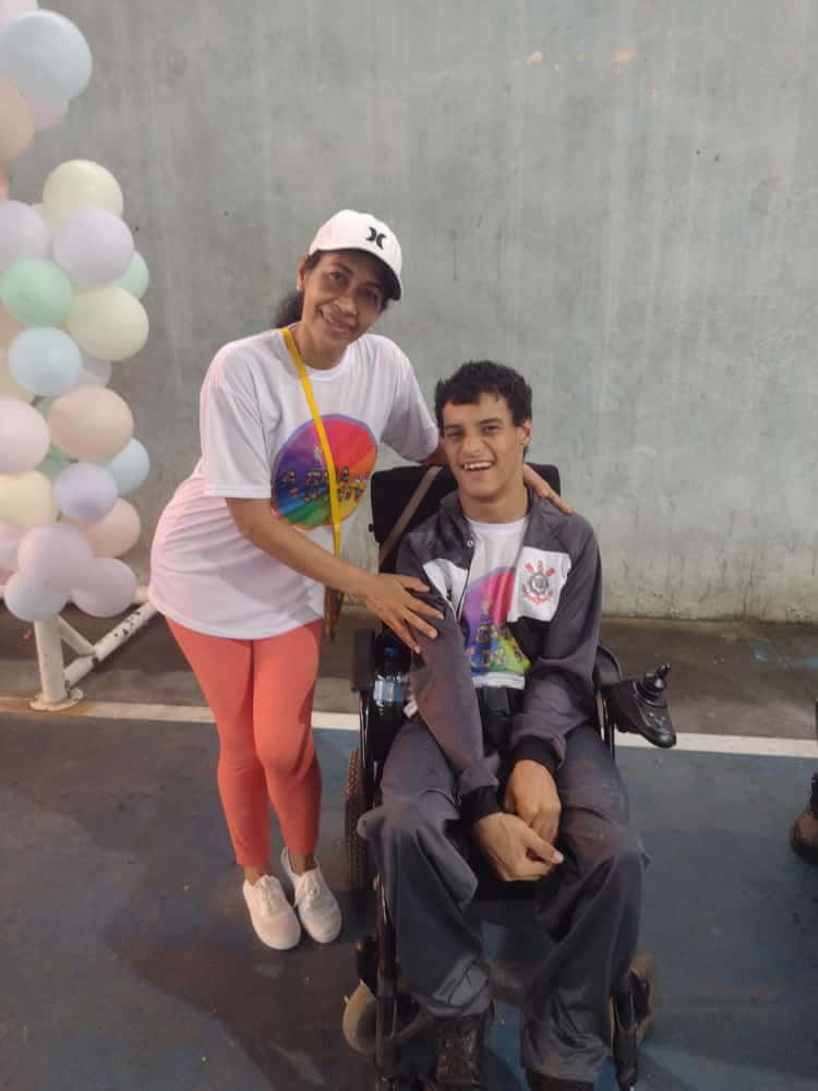 Evento do Dia das Crianças com várias crianças e adultos sentados em cadeiras de plástico em frente a uma mesa com lanches.
