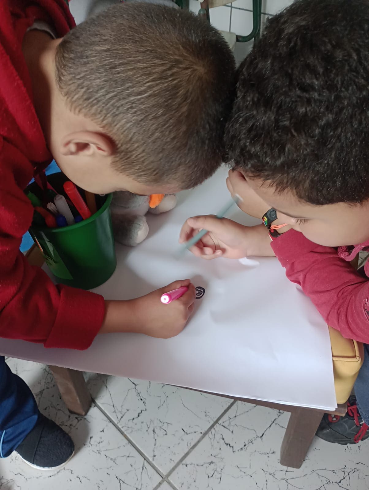 Uma professora de psicopedagogia conversa com uma aluna que está com um giz na mão.